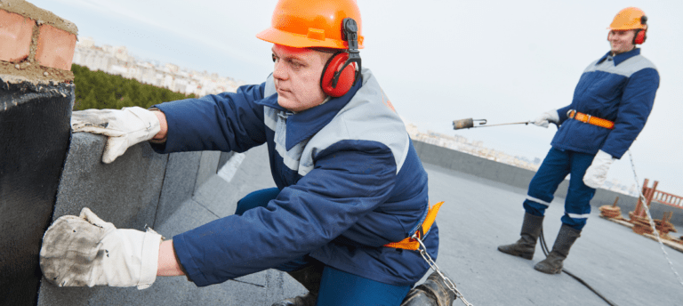 A man wearing an orange helmet and ear muffs.