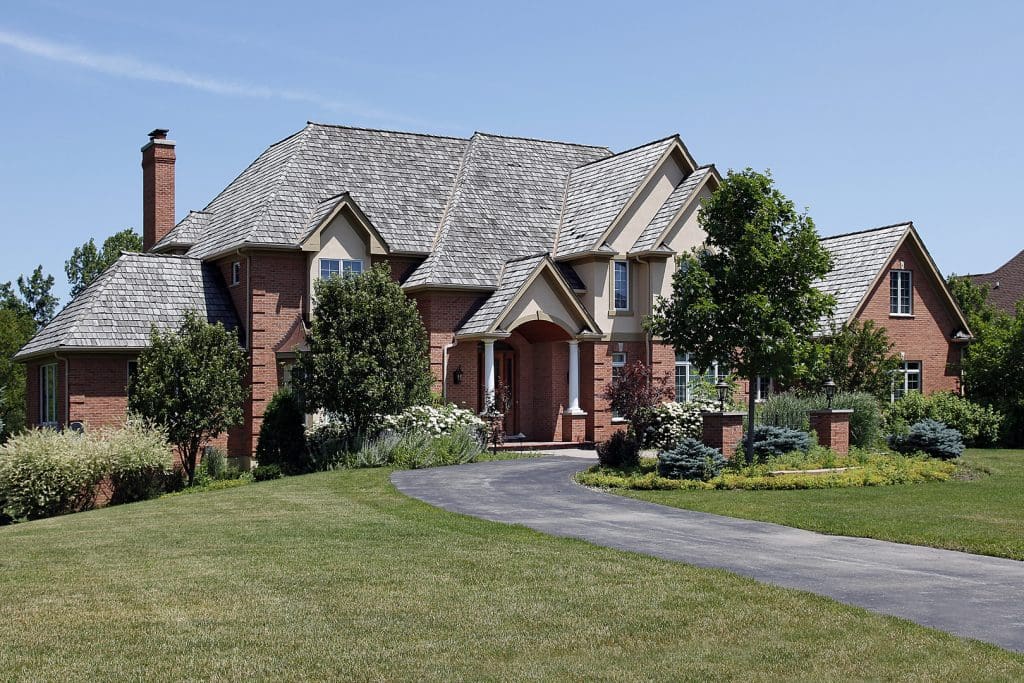 A large brick house with a driveway and lawn.