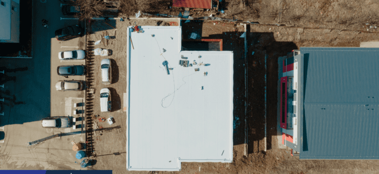 A white building with many pieces of construction equipment on it.