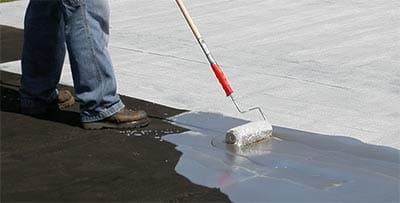 A person painting the floor with a roller.